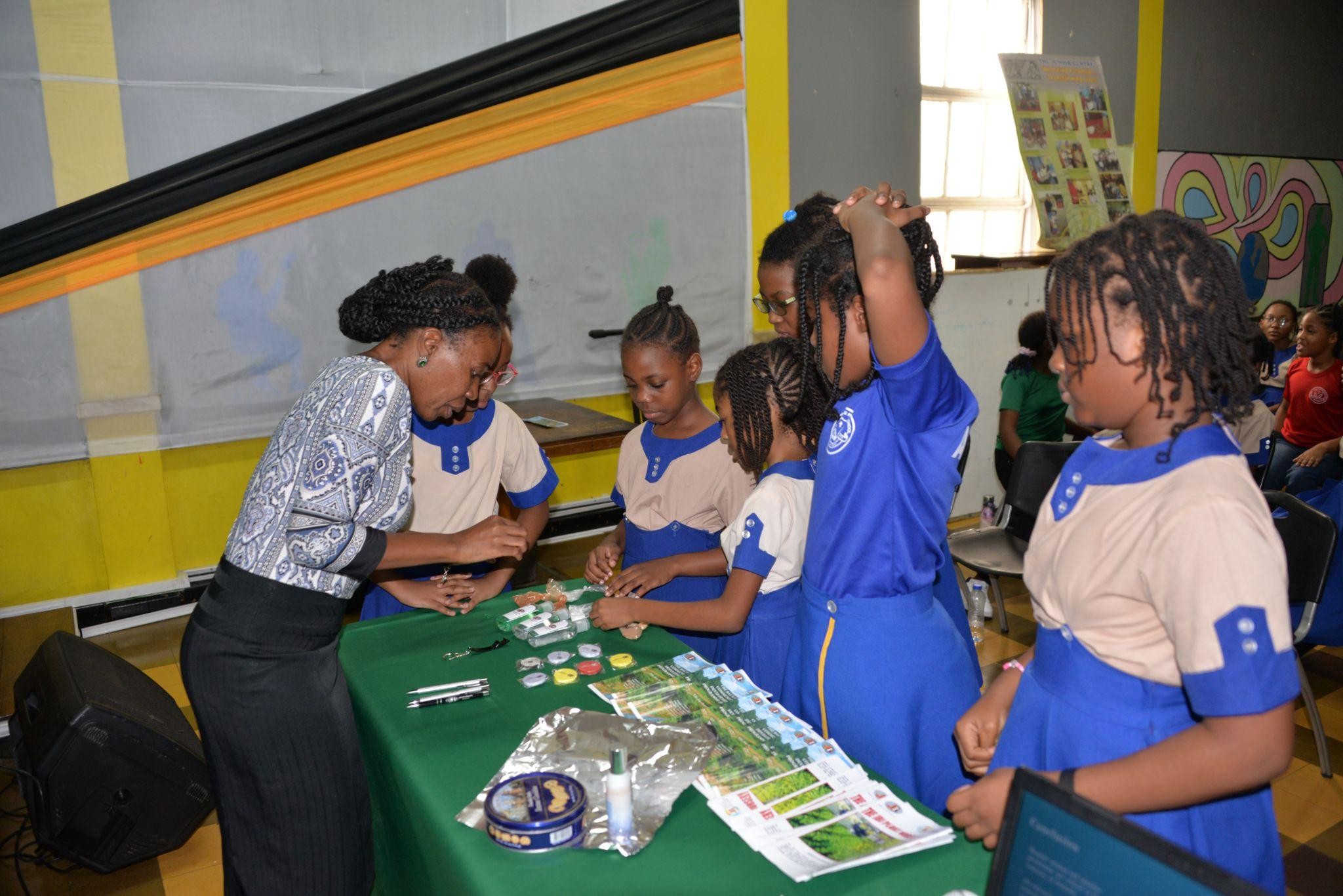 NH_8 Ms. Tandose Sambo from Jamaica Bauxite Institute showing students of the Holy Childhood Preparatory School types minerals that can be found in Jamaica during “ An Afternoon with a Scientist” session.